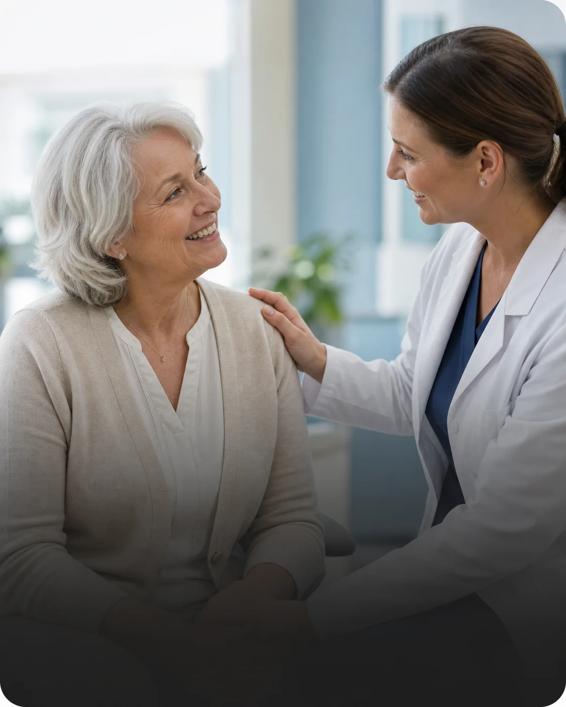 A clinician reassures a smiling patient in a bright clinic room